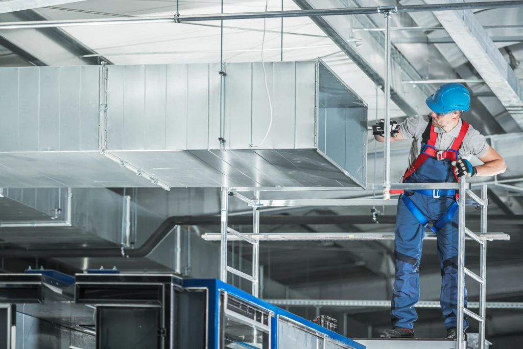 Engineer inspecting commercial ventilation ductwork while working at height